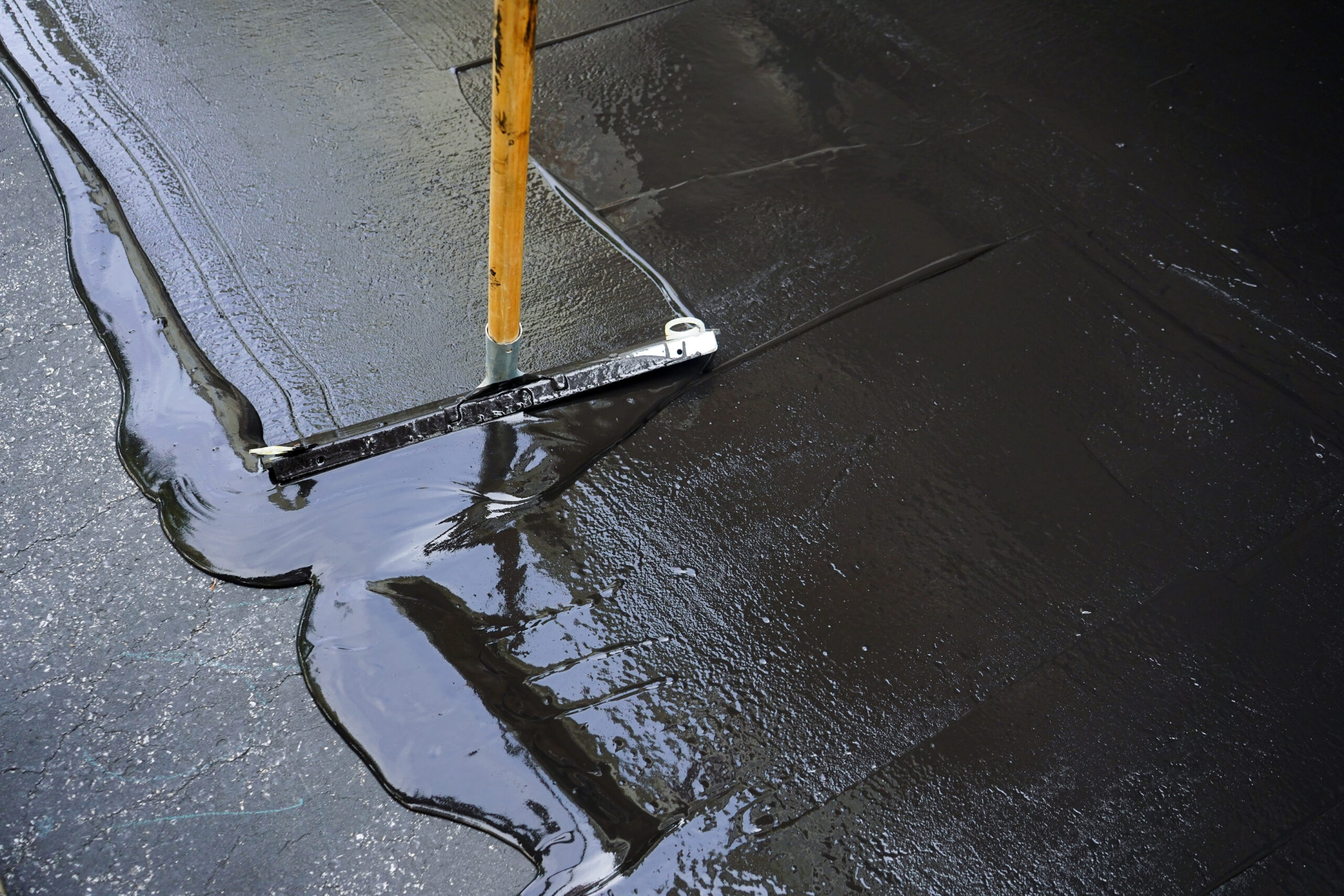 Asphalt sealcoating application with squeegee tool