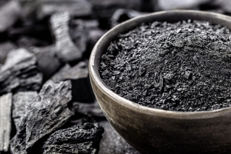 Charcoal in a ceramic bowl with crushed pieces in the background