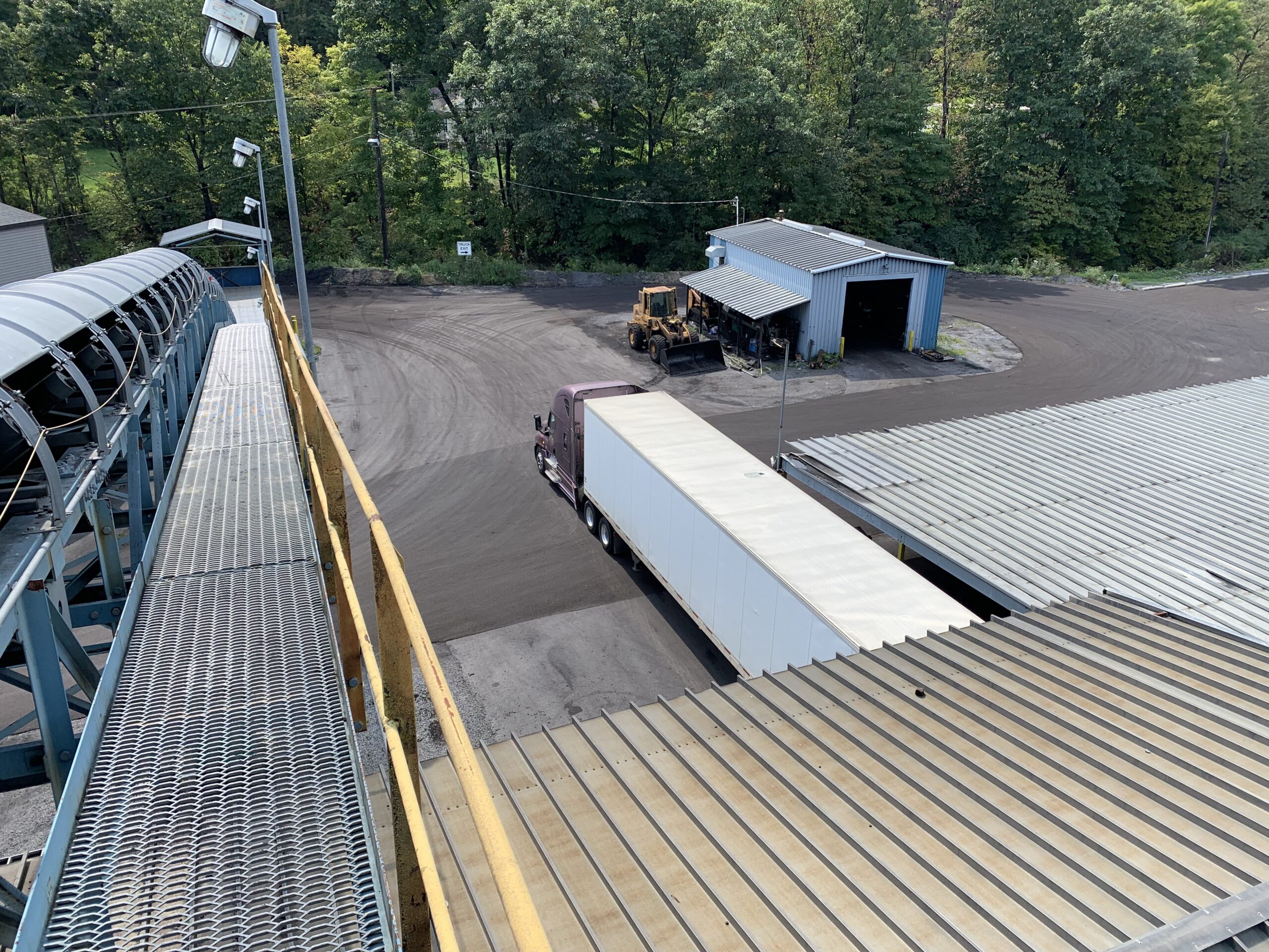 Industrial facility overview with a truck loading area and equipment in the yard