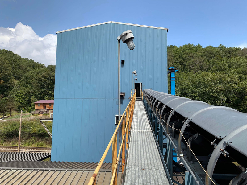 Industrial facility with a blue building and a covered conveyor system walkway