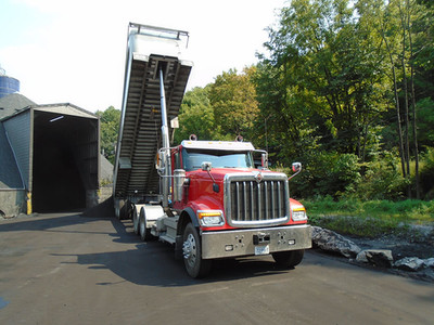 Red dump truck unloading coal at an industrial site