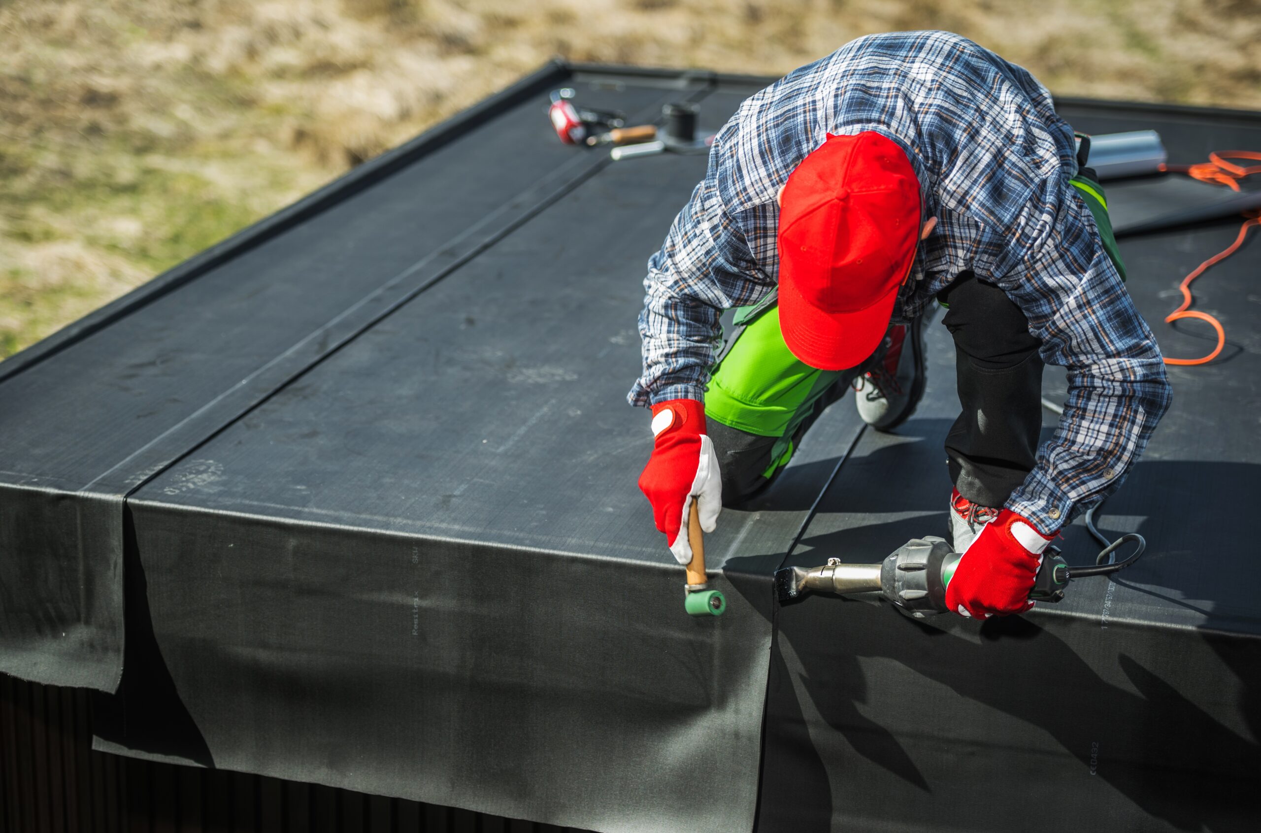 Worker installing waterproofing membrane on a flat roof surface