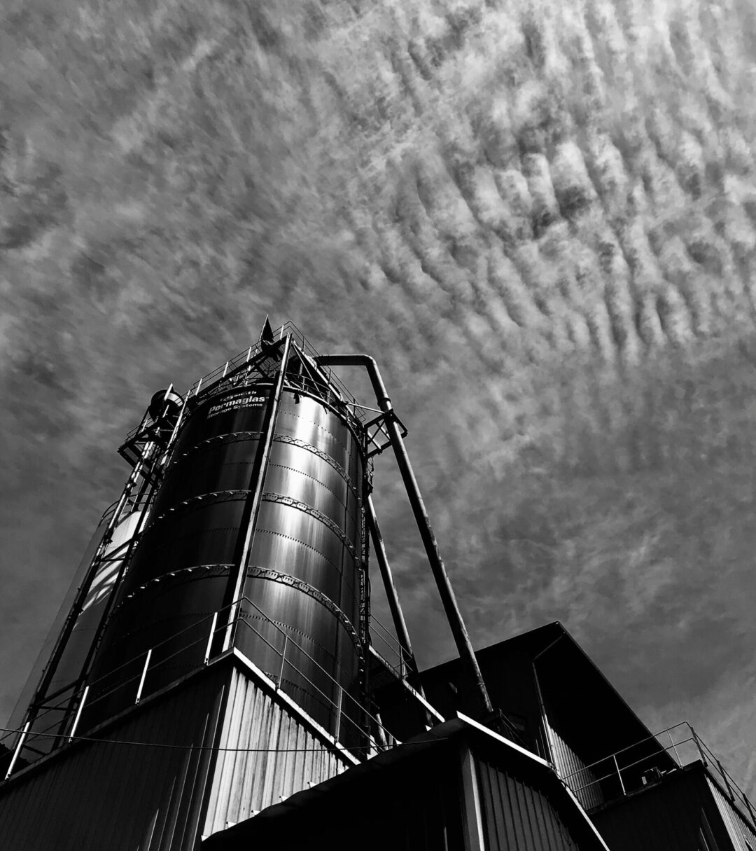 Industrial plant with a silo captured in black and white under a cloudy sky